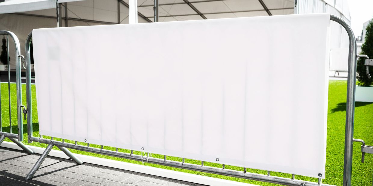 Empty white banner on metal barriers outdoors.