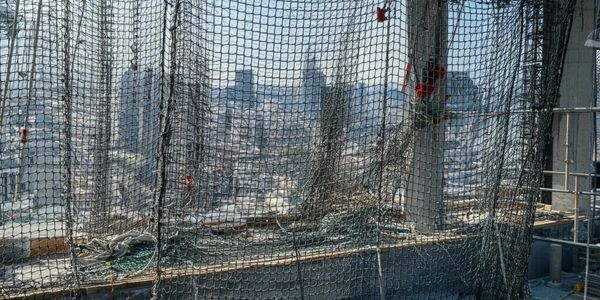 Safety netting installed on a high-rise construction site overlooking a city skyline.