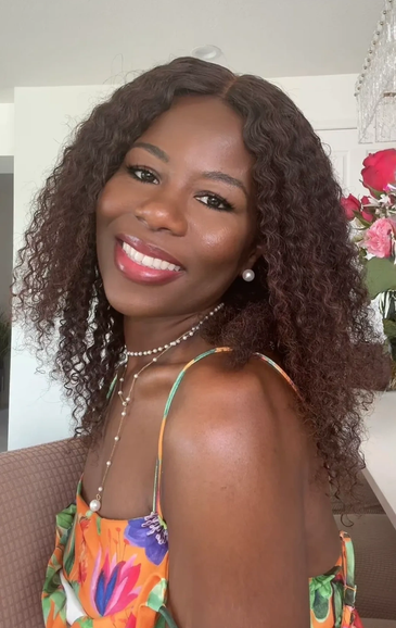 Smiling woman with curly hair in a colorful dress.