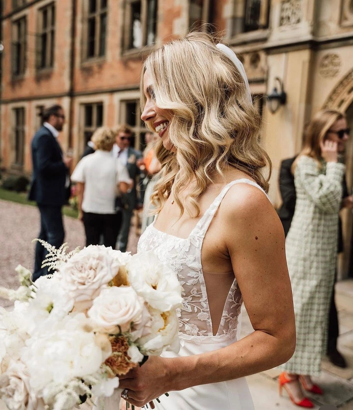 Smiling bride holding bouquet at outdoor wedding.