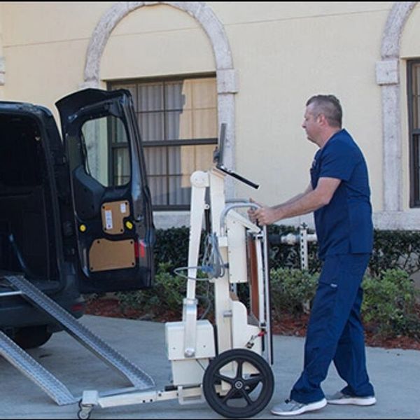 Man loading a medical imaging device into a van with ramps.