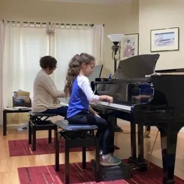 Suzuki Piano student plays with teacher at piano lesson