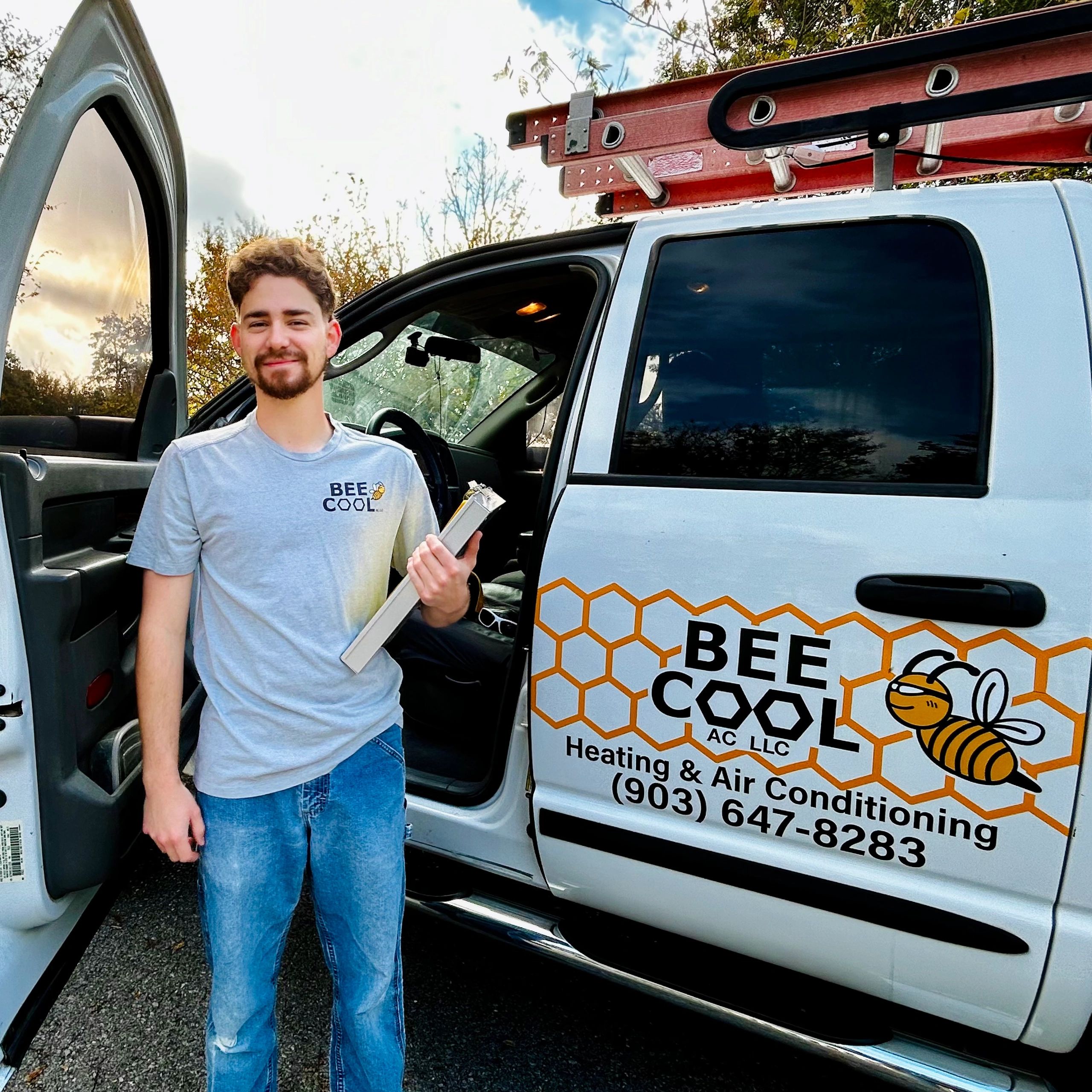 Man standing next to a service van holding a tool.