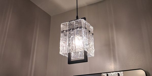 Modern pendant light with textured glass panels illuminating a room.