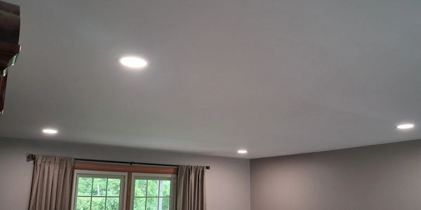 Ceiling with three recessed lights and a window with curtains.