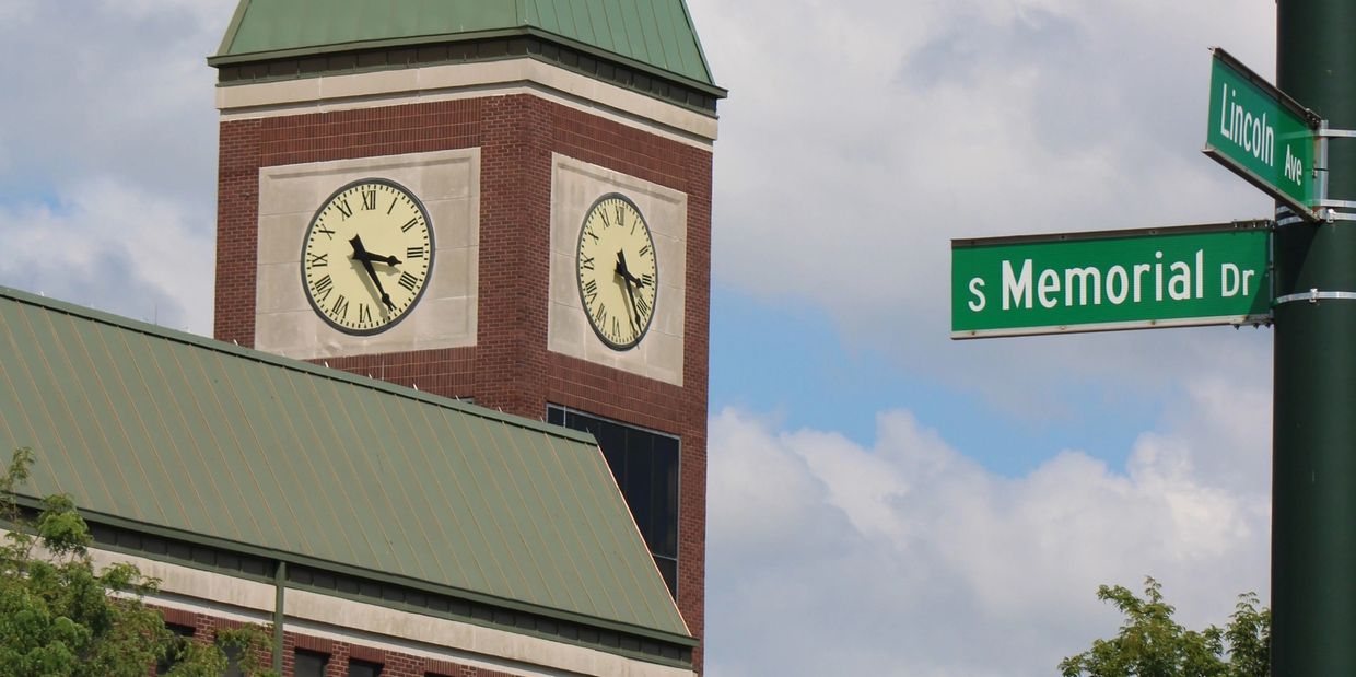 A town clock tower rises above rooftops and trees on a sunny day Lancaster Ohio