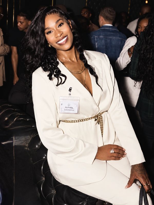 Woman in white blazer smiling at an event.