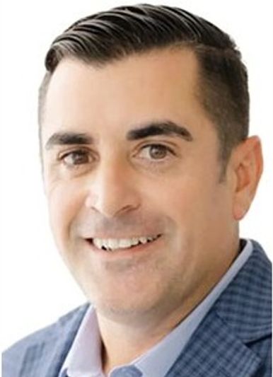 Portrait of a smiling man in a blue checkered blazer.