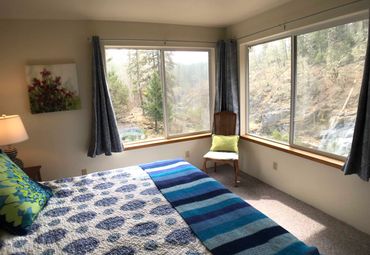 The Riverside bedroom, with windows looking out at the Applegate River and a comfortable king bed.