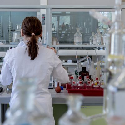 Female in white coat working in a lab.