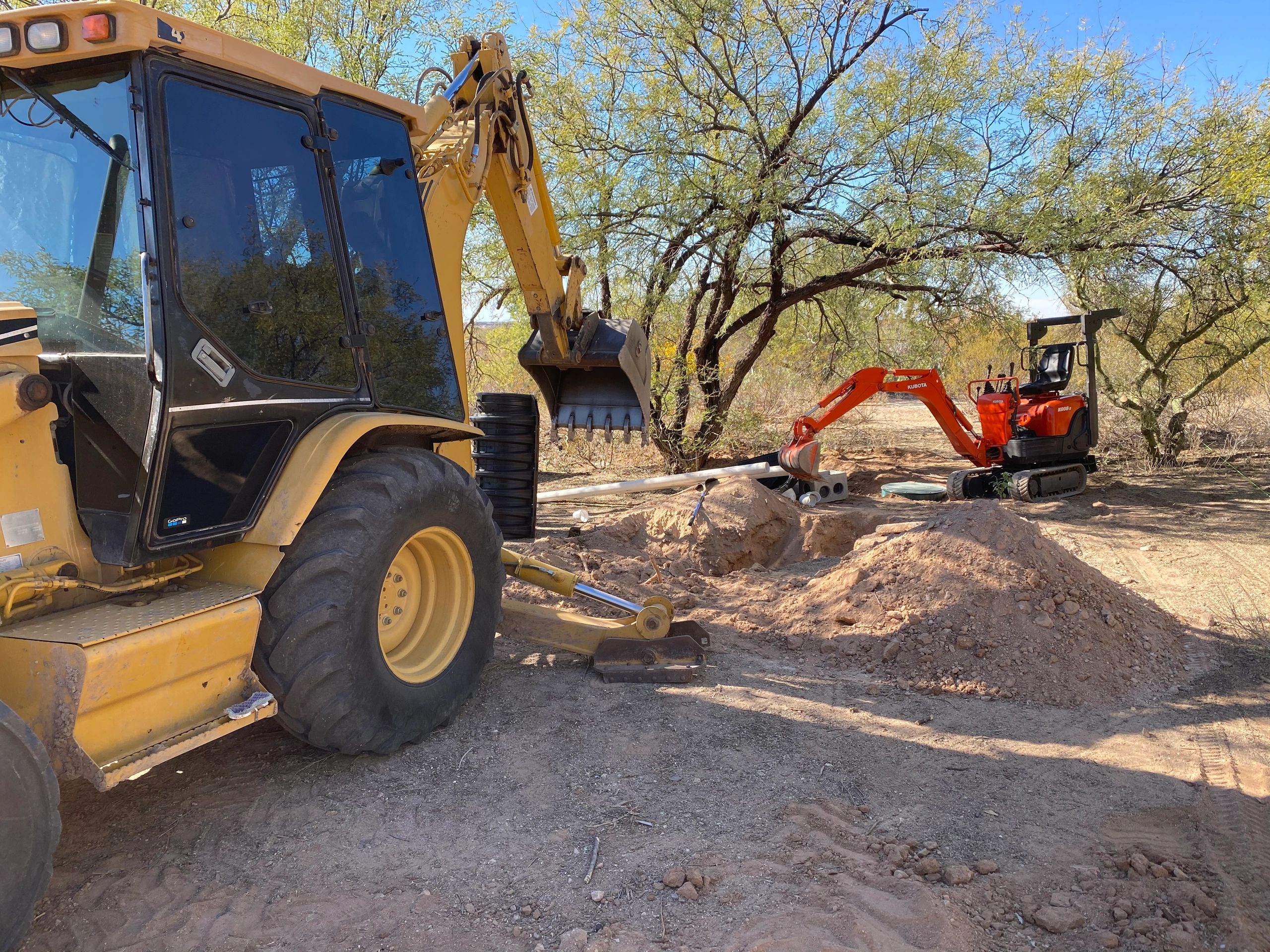 Backhoe & mini excavator performing a leach field repair in Tucson. Also known as leach line repair.