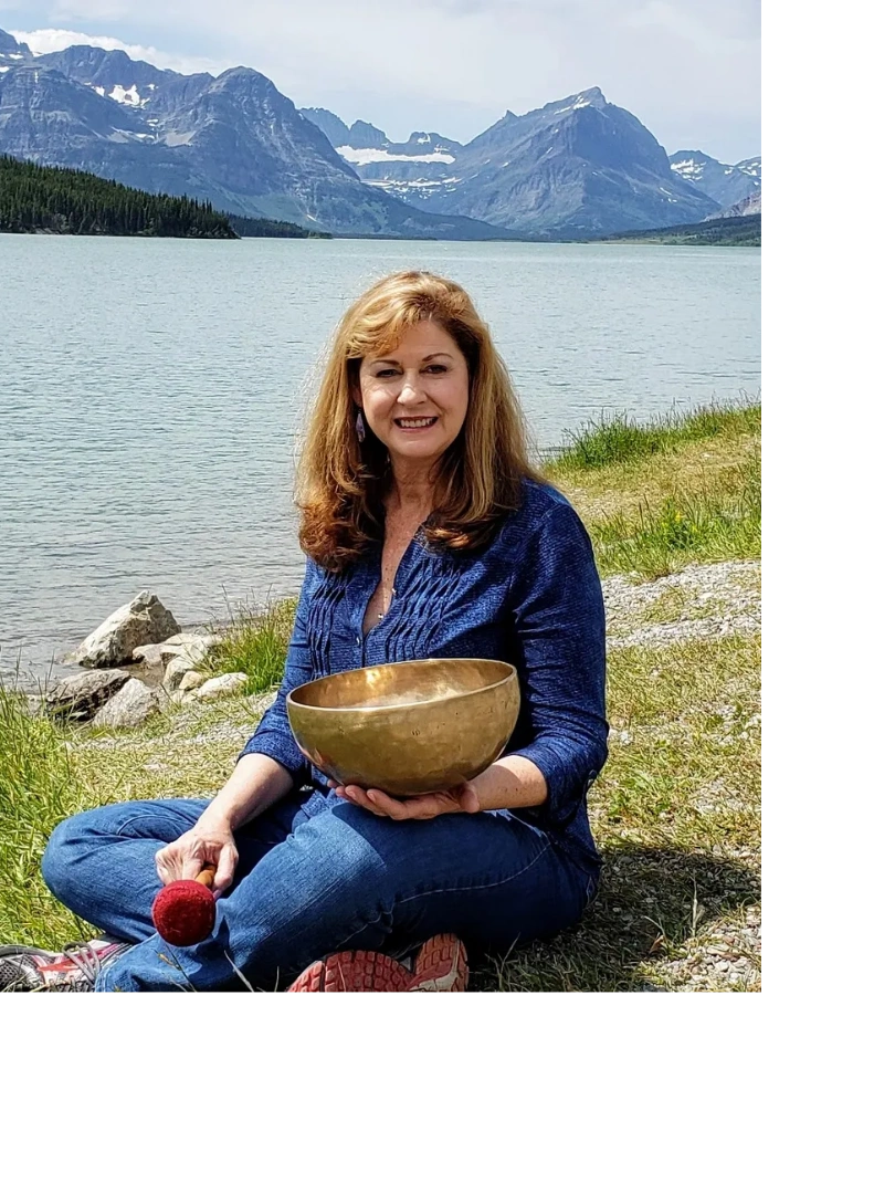 Ann Martin sitting with Singing bowl with mountains behind