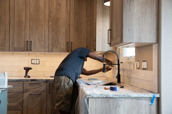 African American male installing backsplash tile for a home renovation project.