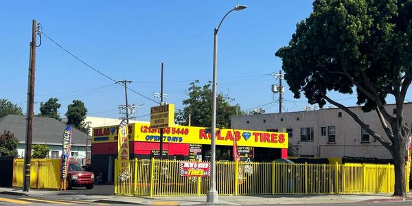 Kulas Tires auto repair shop with bright yellow and red signage on a sunny day.