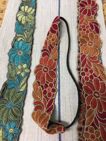 Colorful floral embroidered fabric strips on a textured background.