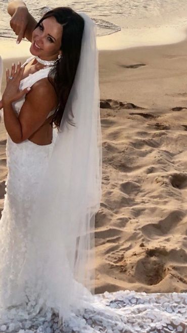 Bride in a white wedding dress and veil on a sandy beach.