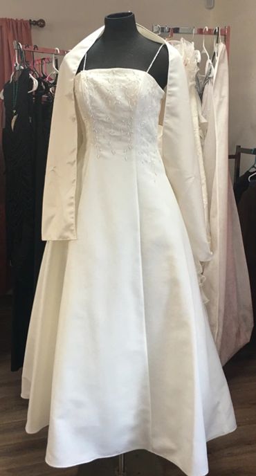 Elegant white wedding dress with a matching jacket on a mannequin.