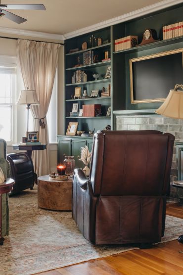 Cozy living room with leather chairs and built-in bookshelves.