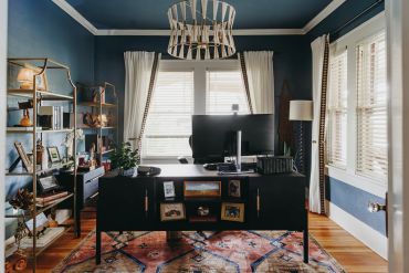 Modern home office with blue walls and a black desk.