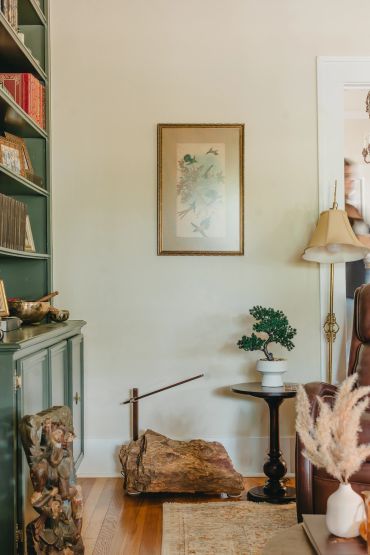 Cozy living room corner with bonsai, wooden decor, and framed artwork.