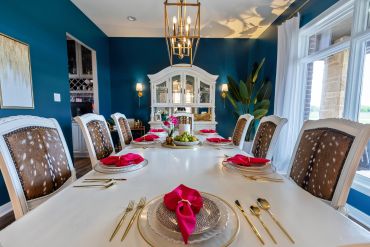 Elegant dining room with a long white table and blue walls.