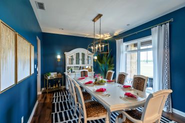 Elegant dining room with a long table, blue walls, and stylish decor.