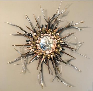 Starburst mirror created from twigs and seashells surrounding fractured mirror