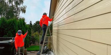 Image of two workers spray painting a house. 