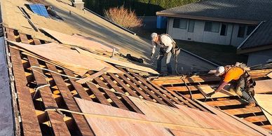 Image of two workers on top of a roof making repairs.