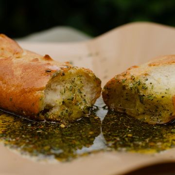 Garlic bread split open, soaked in herb-infused oil.