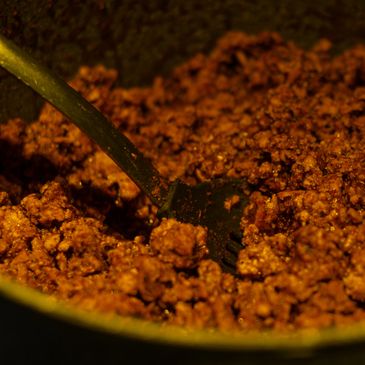 Ground beef cooking in a pan with a spatula.