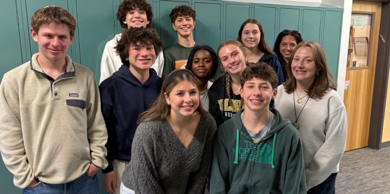 Group of smiling teenagers standing in front of lockers.