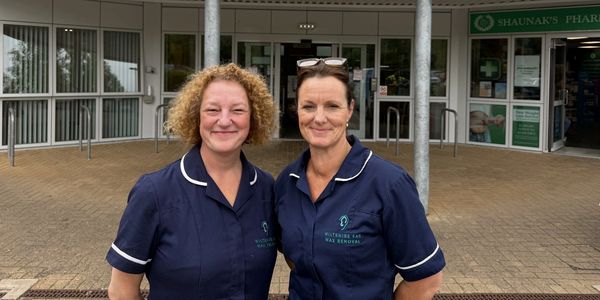 Two women in navy uniforms standing outside a building.