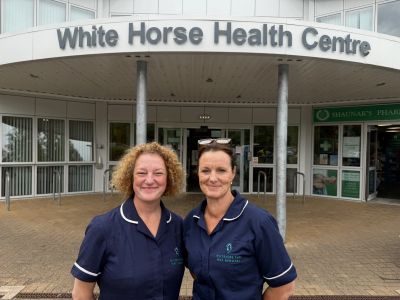 Two healthcare workers stand outside White Horse Health Centre.