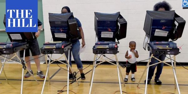 A young child waits alongside voters at several voting booths.