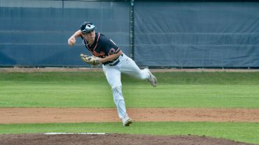 Baseball pitcher in mid-throw on the mound during a game.