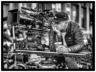 Filmmaker thoughtfully operating a professional camera on set.