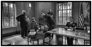 Film crew directing an actor in a military uniform on set indoors.