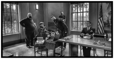 Film crew directing an actor in a military uniform on set indoors.