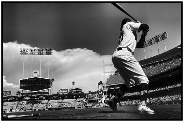 Black and white image of a baseball batter ready to hit in a stadium.