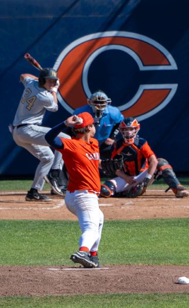 Pitcher in orange uniform throwing a baseball to a batter on the field.