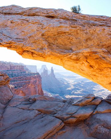Sunrise at Mesa arch and view on the purple mountains. Hike at Canyonlands National Park.