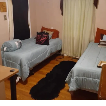 Simple bedroom with two single beds and wooden floor.