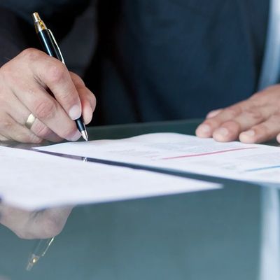 Hand unterschreibt ein Dokument mit Füller