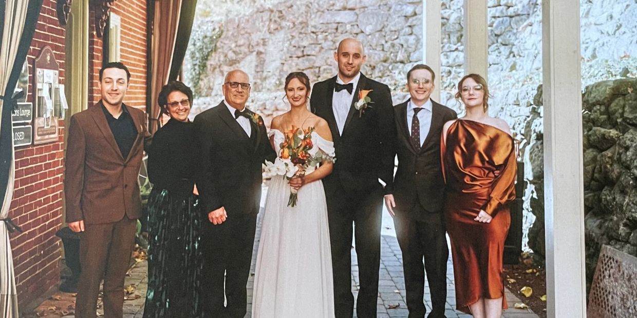 Elegant wedding party posing outdoors with the bride and groom at center.