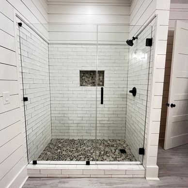 Modern walk-in shower with glass doors and pebble stone floor.