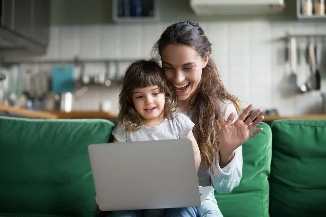 woman with her daughter waving at the laptop  