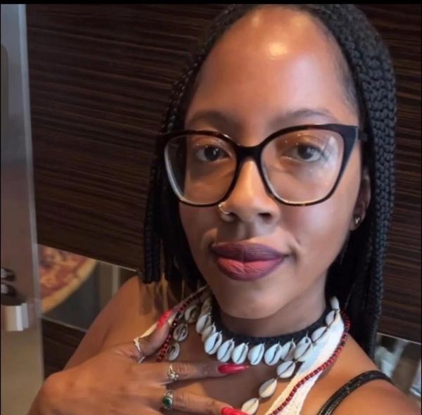 Woman with glasses and braided hair wearing shell necklaces.
