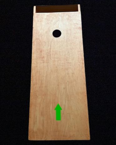 Wooden cornhole board with a green arrow pointing upwards.