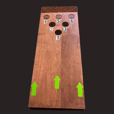 Wooden cornhole board with numbered holes and green arrows.